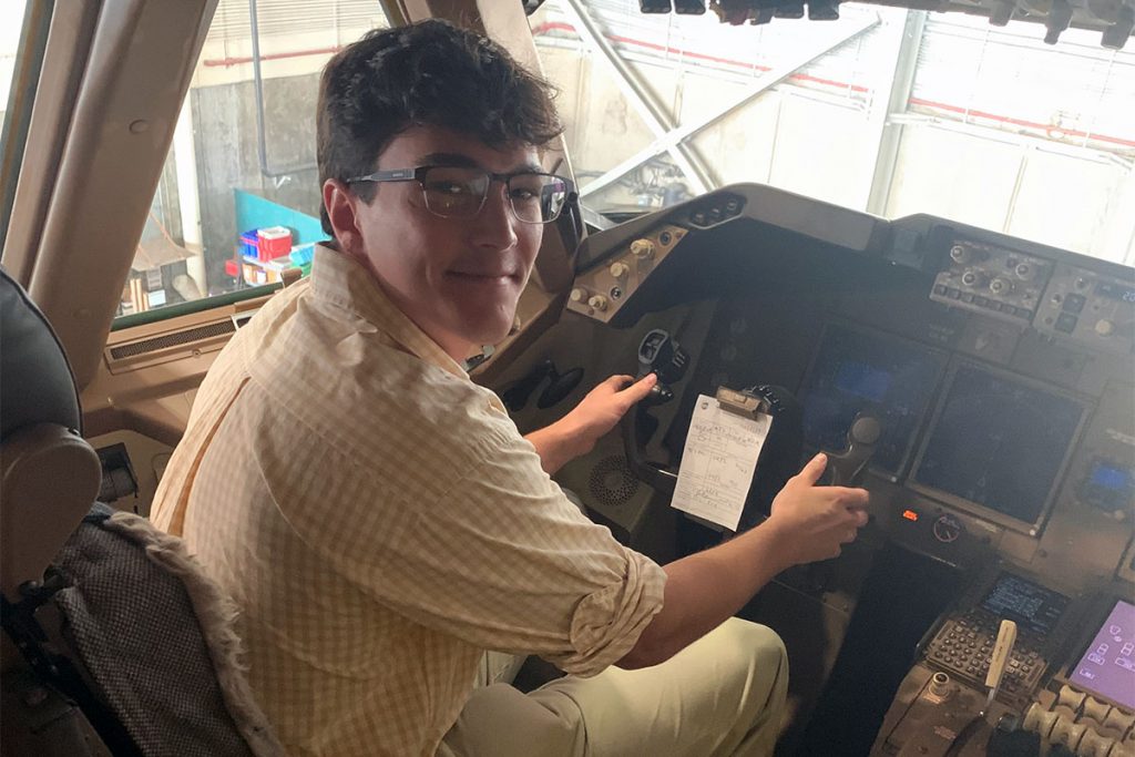 Christopher Schenck sits in the pilot seat with both hands on the controls of an aircraft used by UPS.