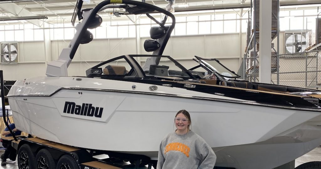 Autumn Cox standing in a warehouse next to a Malibu boat