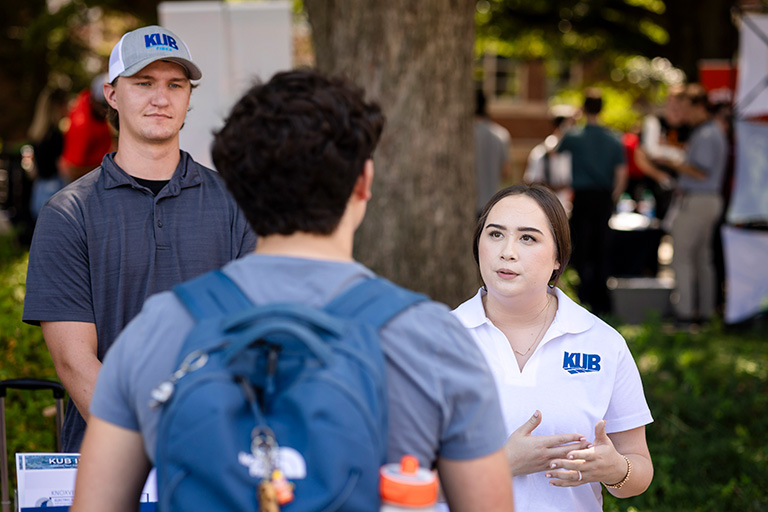 Male and female KUB representatives speaking with male student