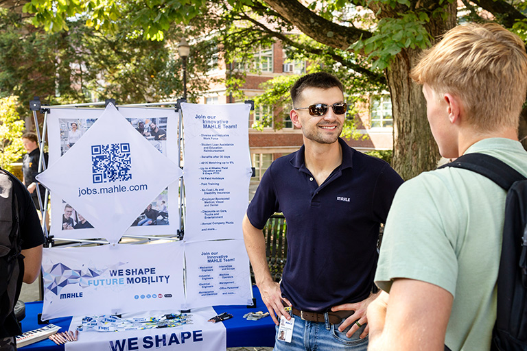 Mahle employee representative speaking with a male student at the Engineering Cookout