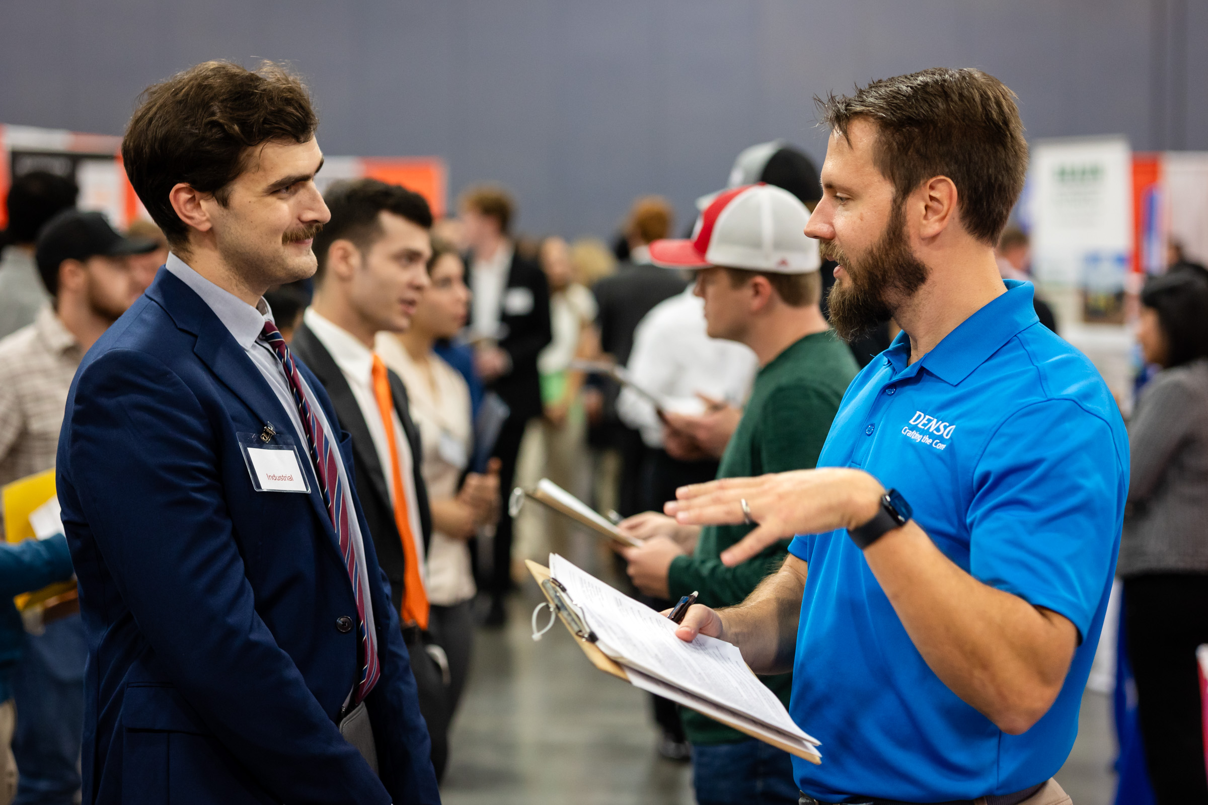 Denso representative speaking with a male student at the Engineering Expo