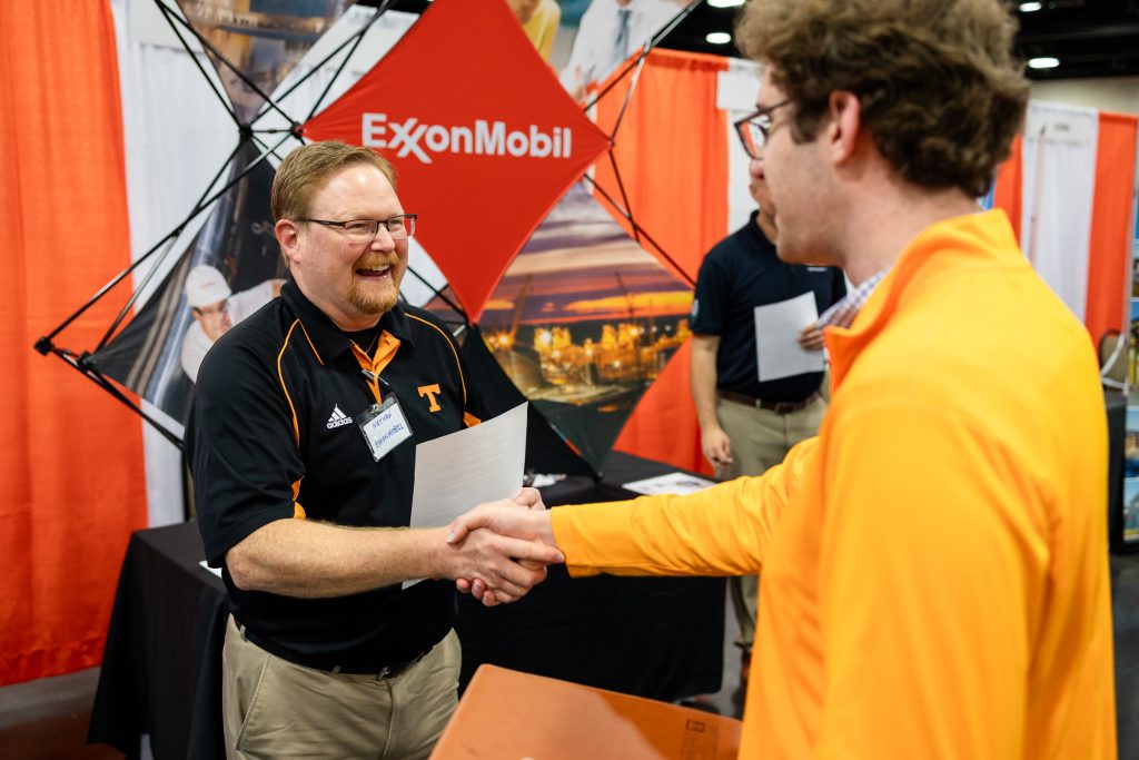 Exxon representative shaking hands with a UT engineering student at Engineering Expo