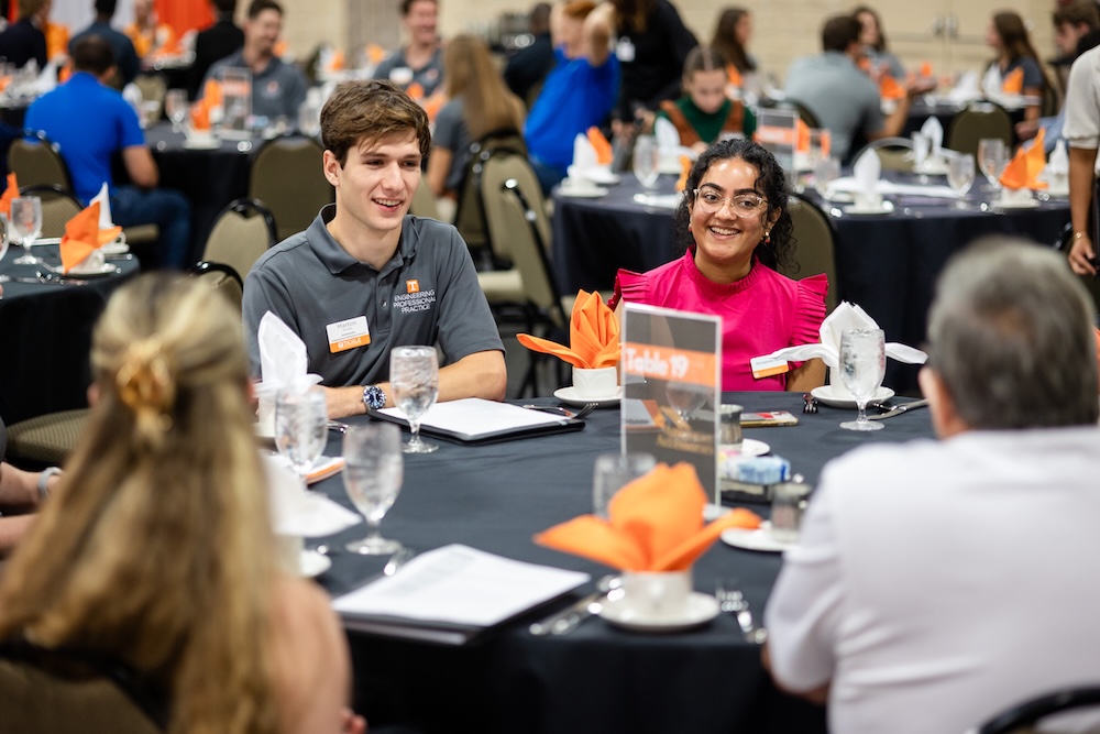 students sitting around a table talking to employers